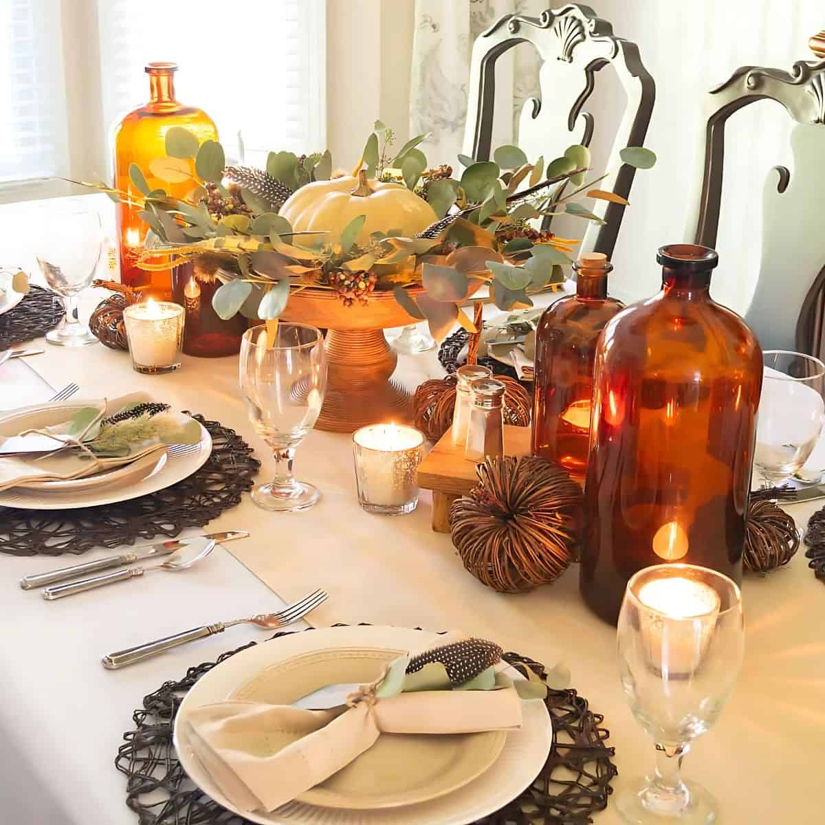 Thanksgiving tablescape with neutral linens and dinnerware and large amber bottles in the centerpiece