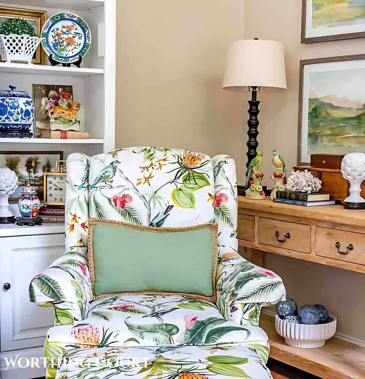 tropical floral print armchair sitting in front of a white entertainment center and pine console table