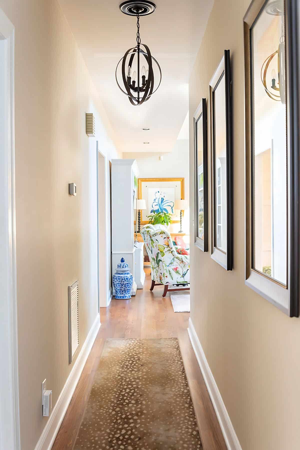 looking down a hallway with an antelope print rug into a living room with colorful traditional furniture and accessories