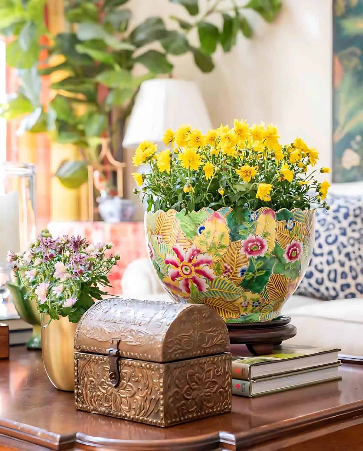 colorful ceramic planter with a yellow mum and other accessories to create a fall vignette on a wood coffee table