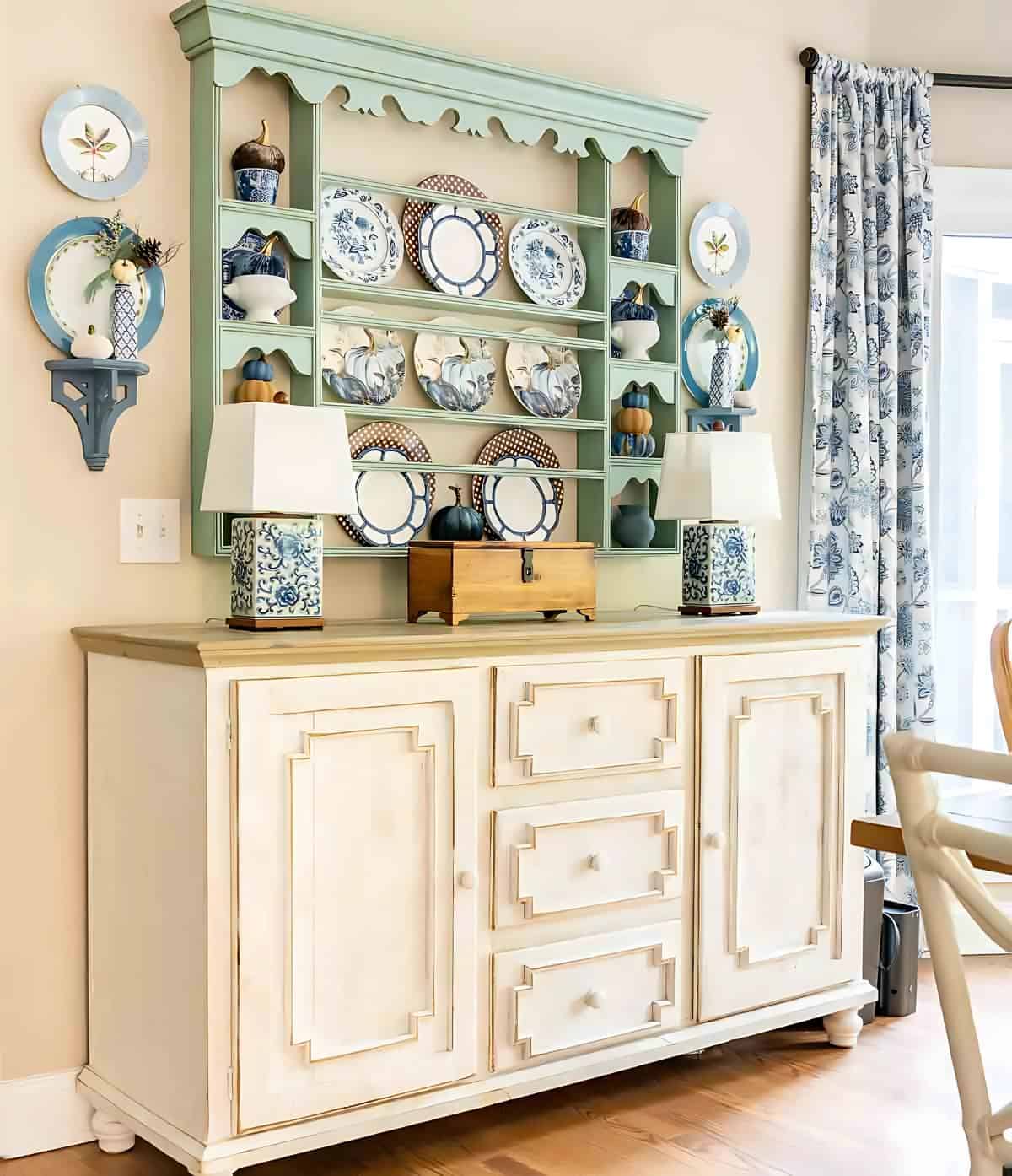 blue, white and brown dishes displayed on a plate rack for fall hanging above a white sideboard