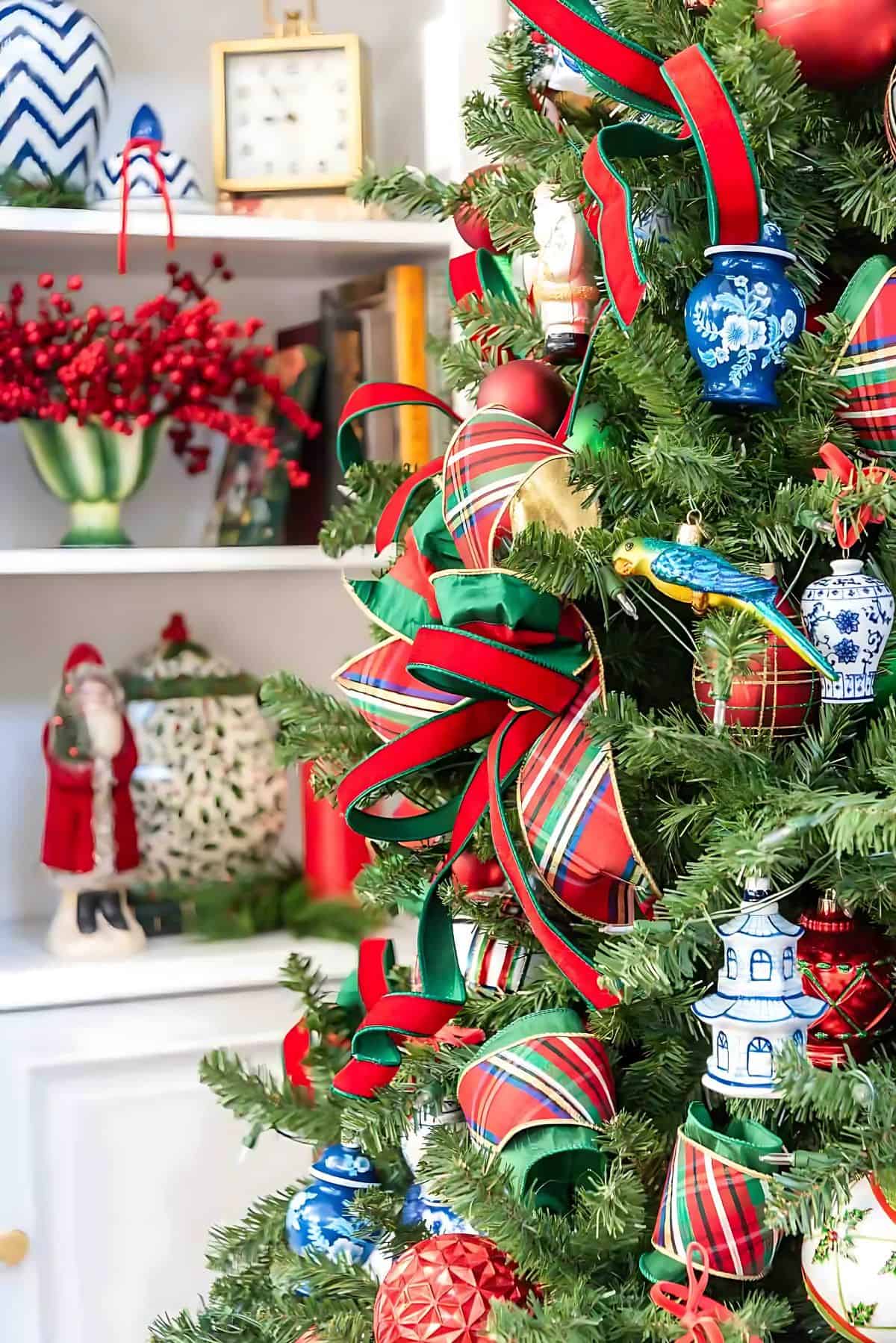 Chinoiserie Christmas tree decorated with red and green ornaments and blue and white Chinoiserie ornaments and tartan plaid ribbon