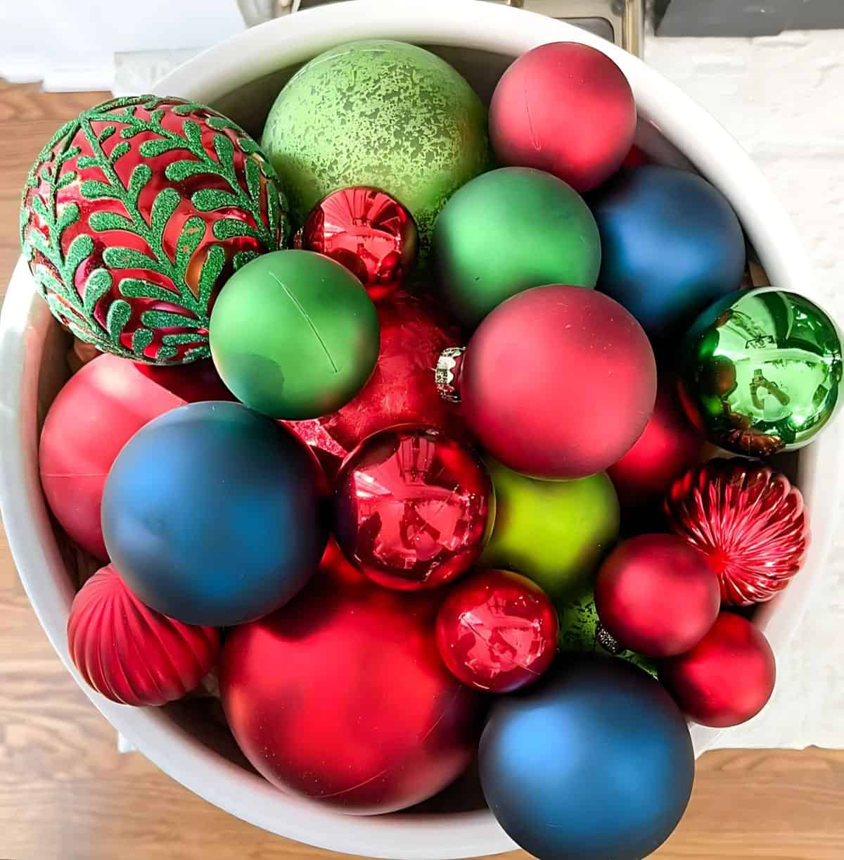 overhead view of large bowl filled with multiple colors of Christmas ornaments