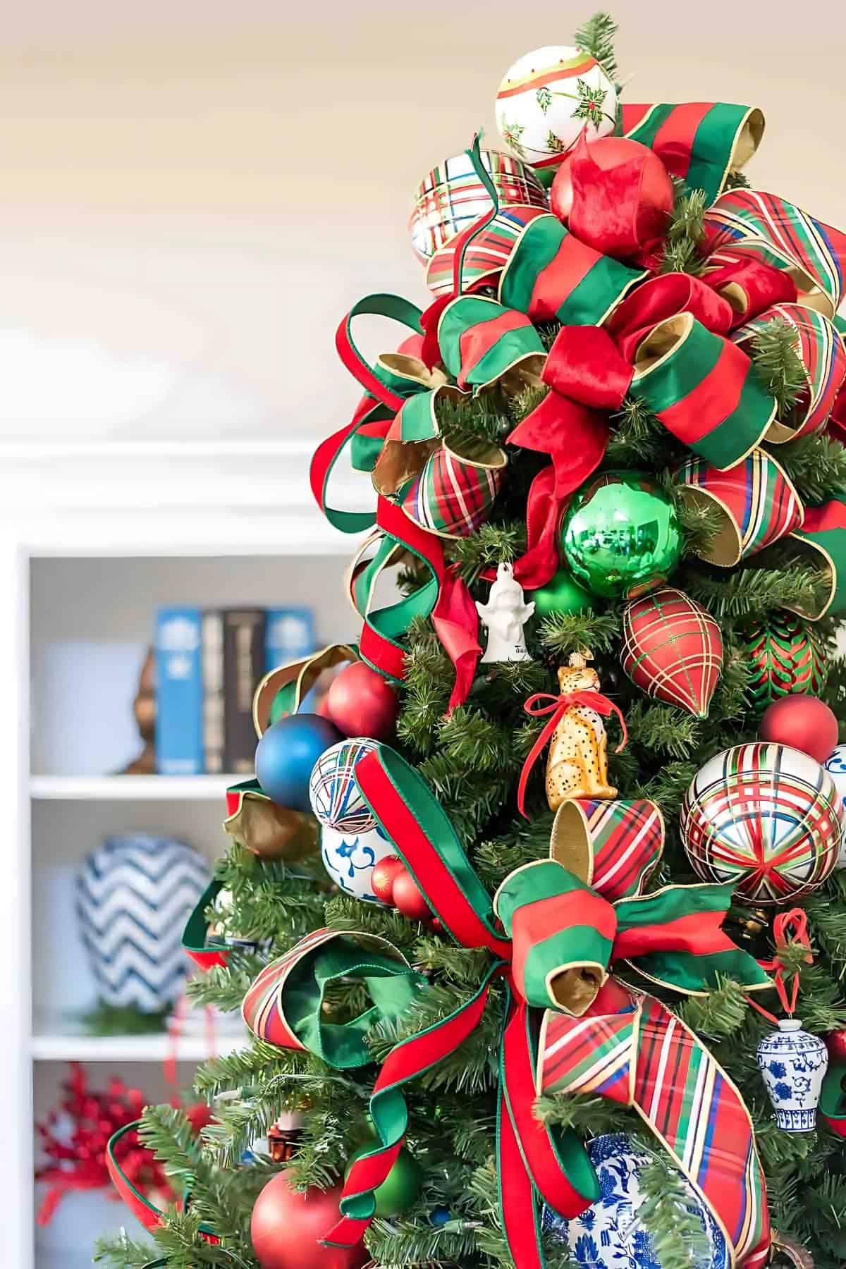 Chinoiserie Christmas tree decorated with red and green ornaments and blue and white Chinoiserie ornaments and tartan plaid ribbon