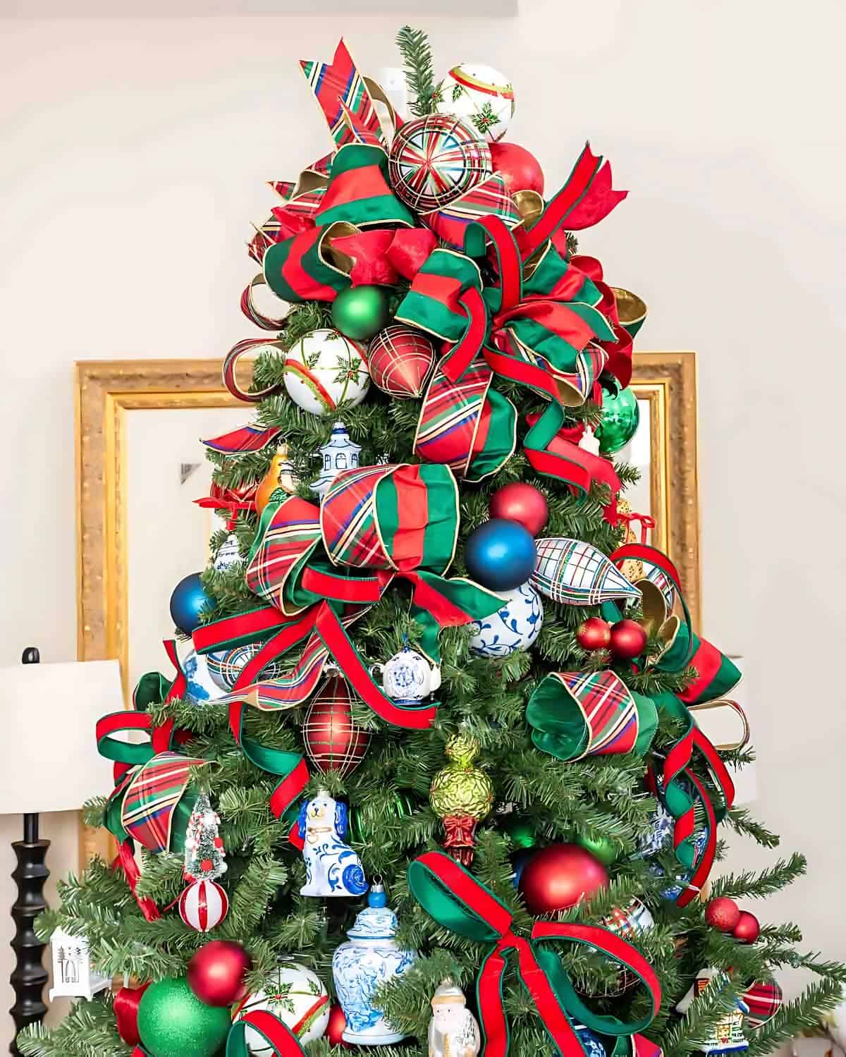 Chinoiserie Christmas tree decorated with red and green ornaments and blue and white Chinoiserie ornaments and tartan plaid ribbon