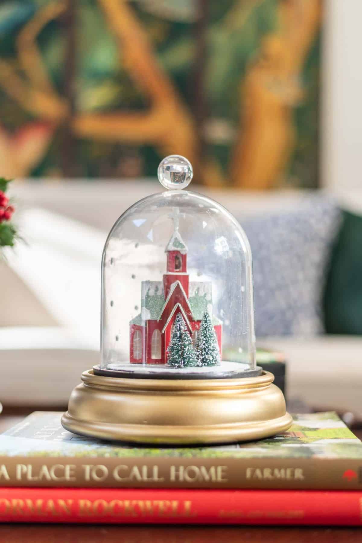 tiny red church under a glass cloche on a gold pedestal