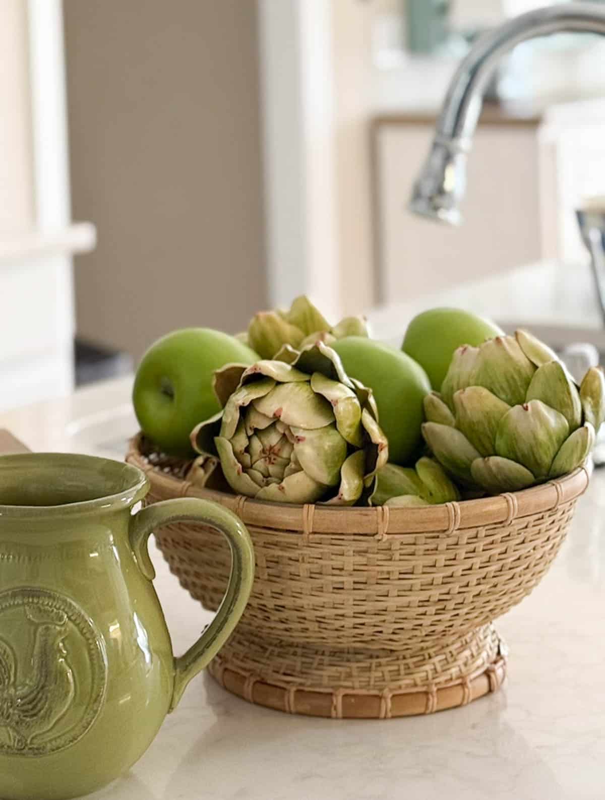 wicker pedestal bowl filled with faux apples and artichokes